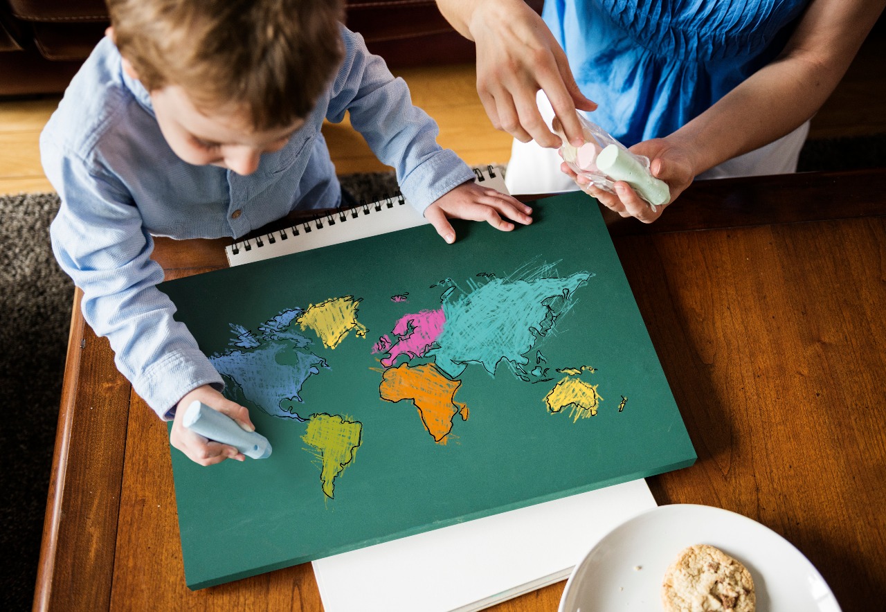 Child learning geography by coloring a world map in class activity